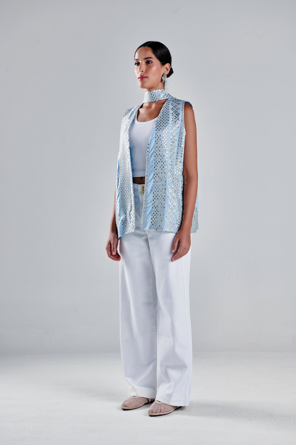 A model stands in a studio wearing a sleeveless light blue patterned vest over a white top and white wide-leg pants, with beige pointed flats. #Baby Blue