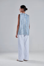 A woman is shown from the back wearing a sleeveless light blue embroidered top with white wide-leg pants, standing against a neutral light gray studio background. #Baby Blue