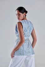 A woman shown from the back wearing a light blue sleeveless top with silver mirror work and white pants, photographed against a plain light gray studio background. #Baby Blue